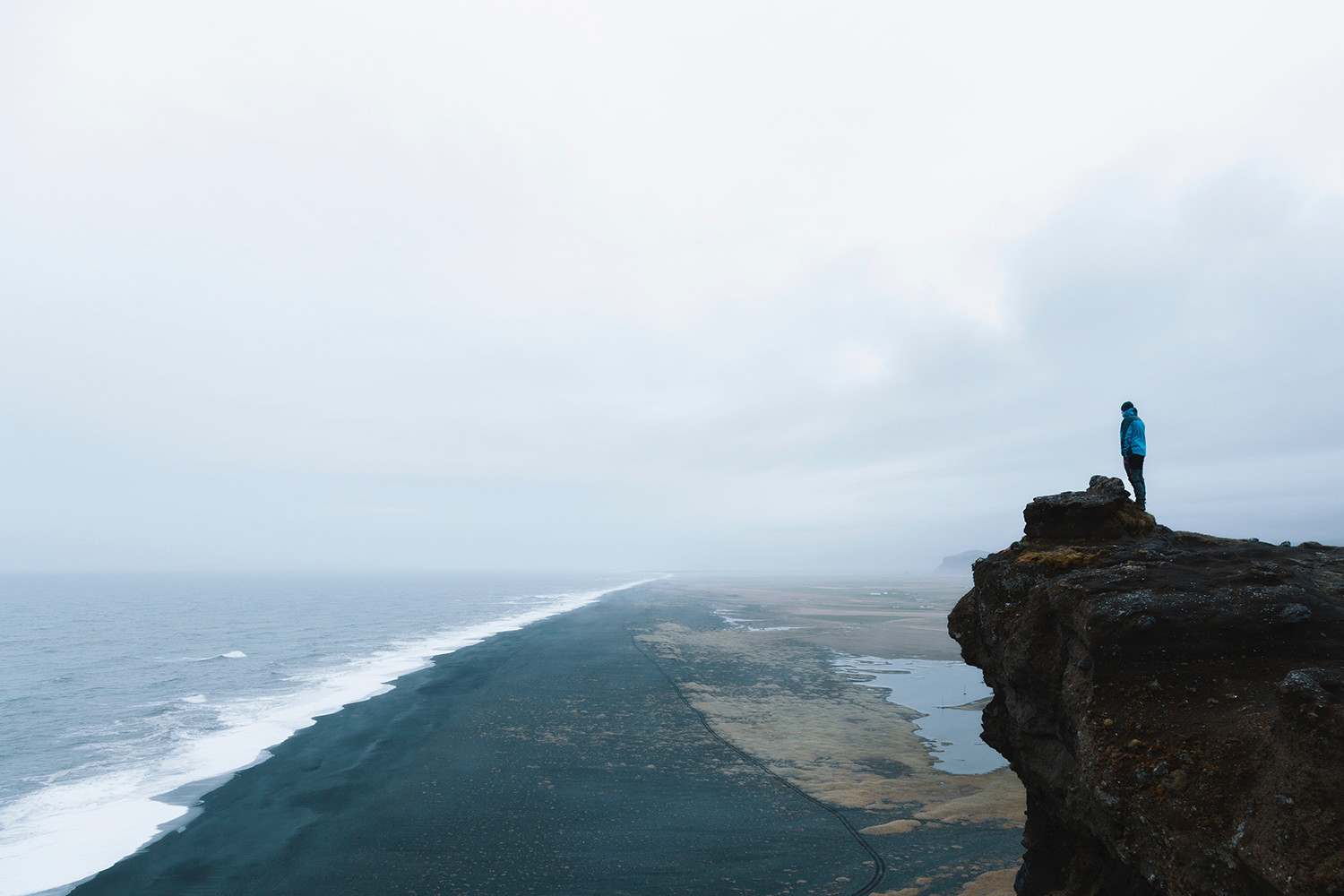 Woman standing on a cliff overlooking the ocean